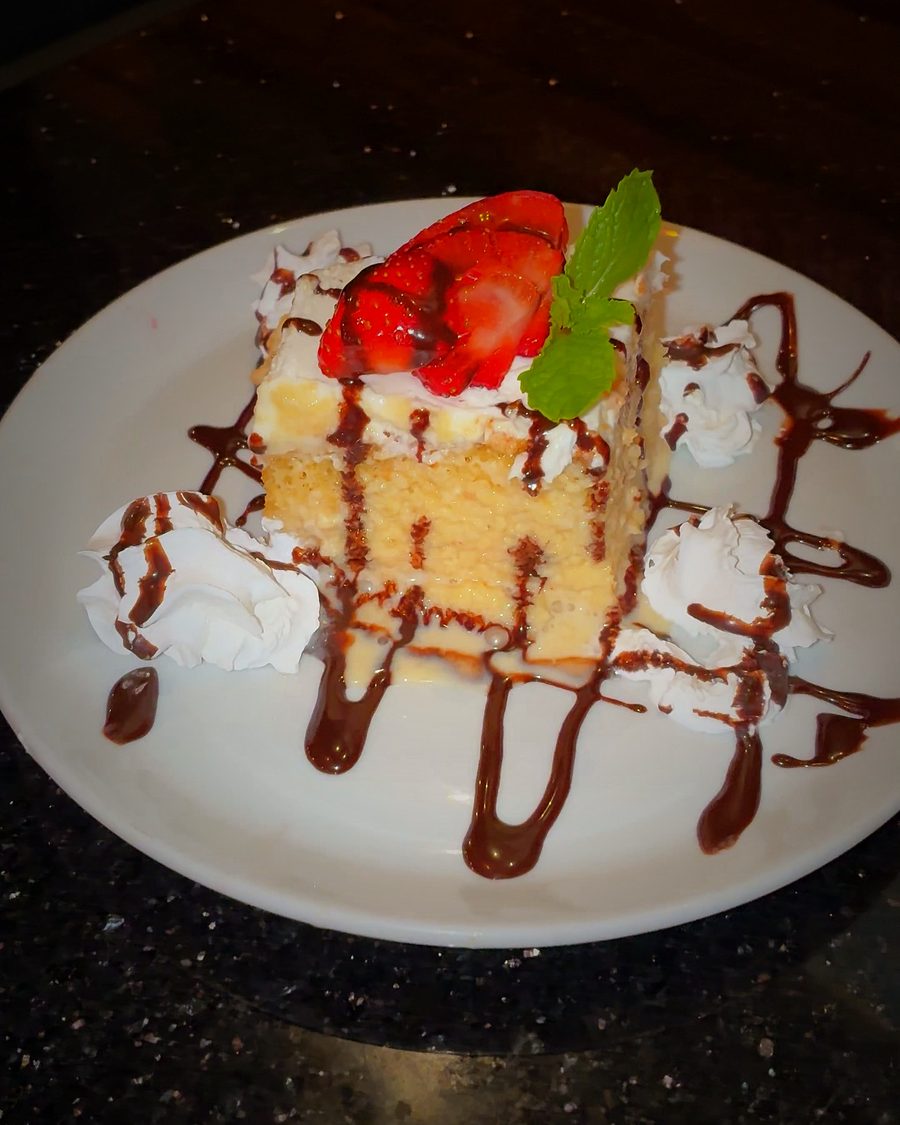 A slice of Tres Leches with strawberry and chocolate