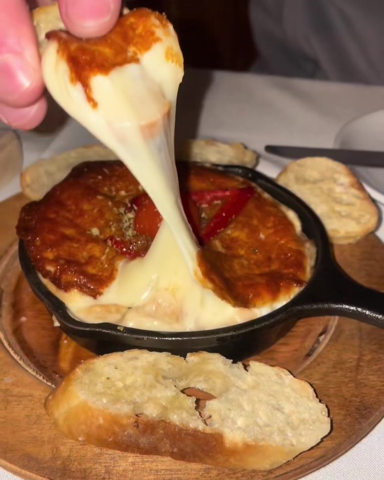 Provoleta, melted provolone being pulled with a fork